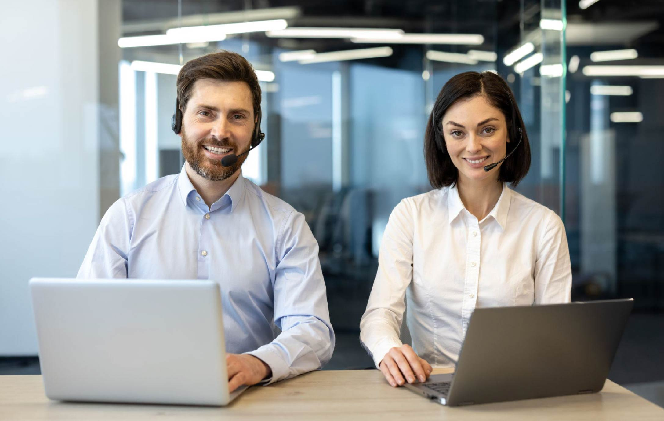 professional customer support team with headsets working on laptops in a modern office environment
